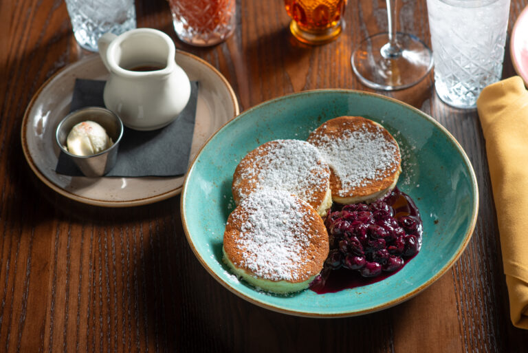 buttermilk pancakes with sprinkles, powdered sugar, and maple syrup